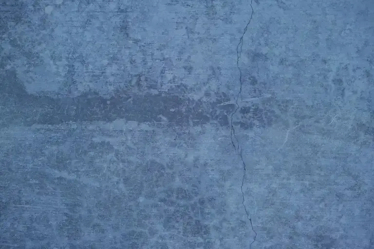 Close-up of a blue concrete surface with visible cracks, representing a garage floor in need of crack repair.