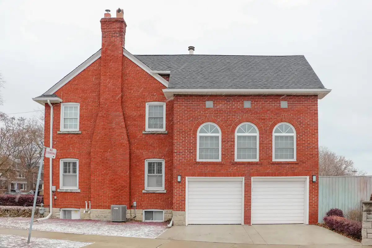 Red brick house with a two-car garage and a snowy driveway