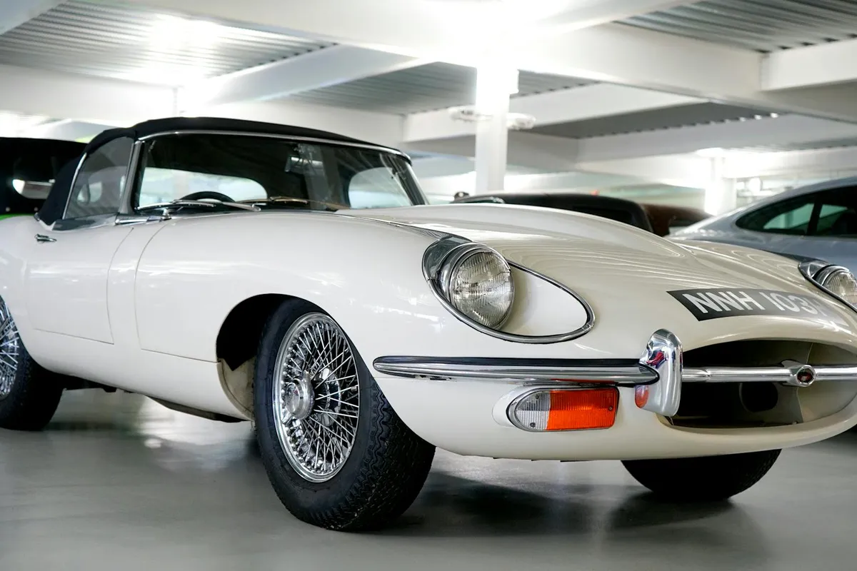 White vintage sports car parked in an indoor parking garage.