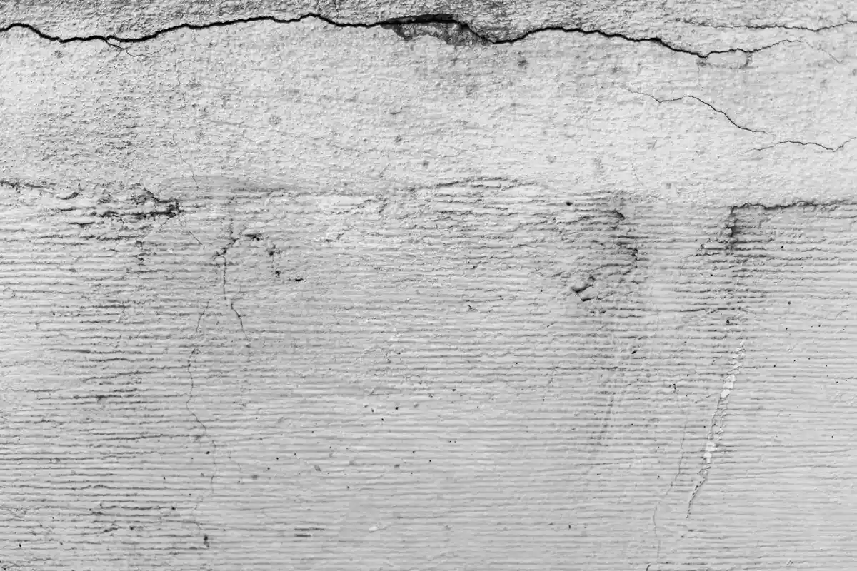 Close-up of a textured concrete surface with cracking and lines, illustrating moisture-related substrate concerns.