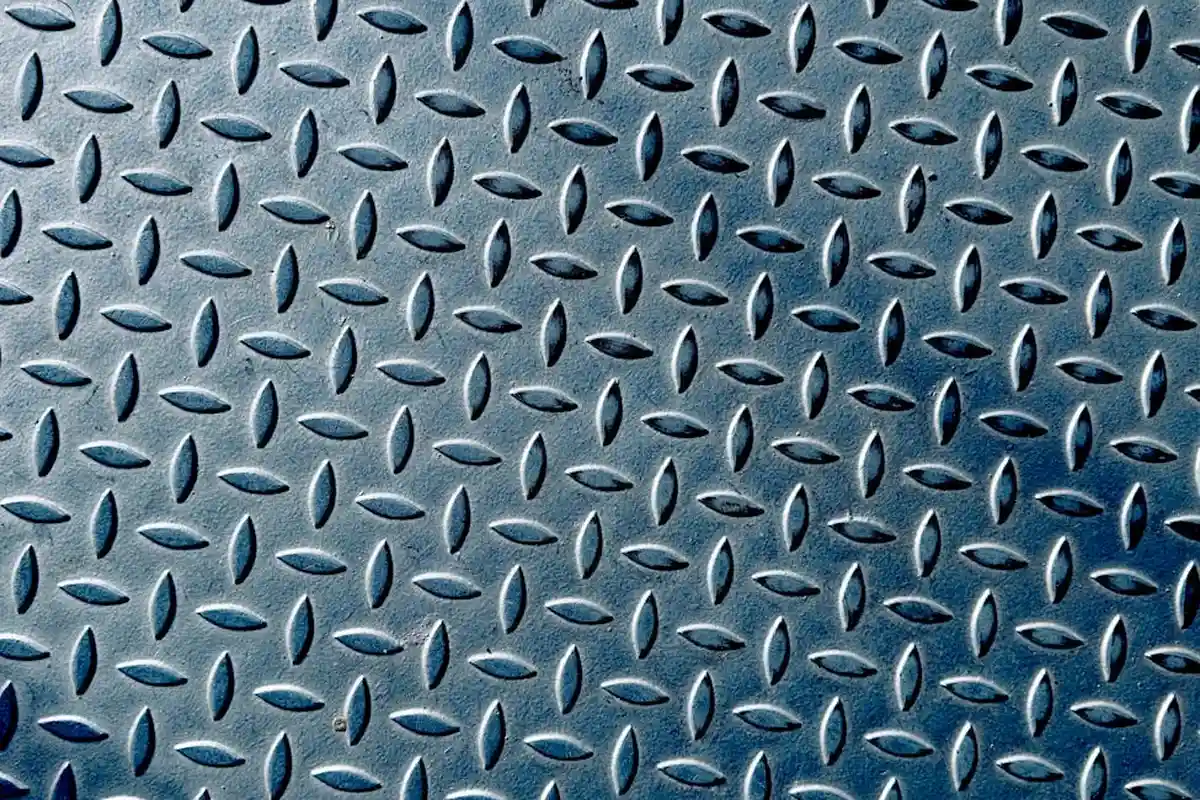 Close-up of a blue-toned diamond-plate metal texture representing a rugged garage floor surface