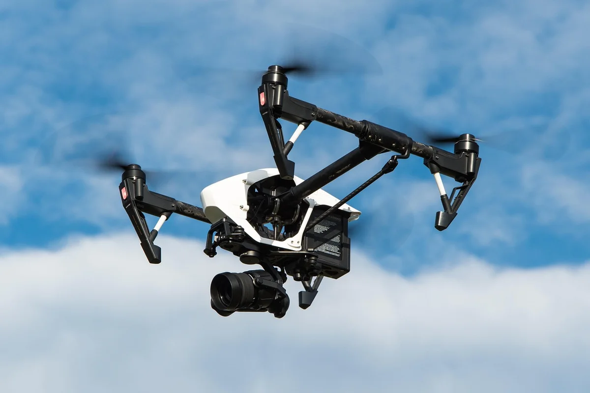 Quadcopter drone with a mounted camera flying in the sky