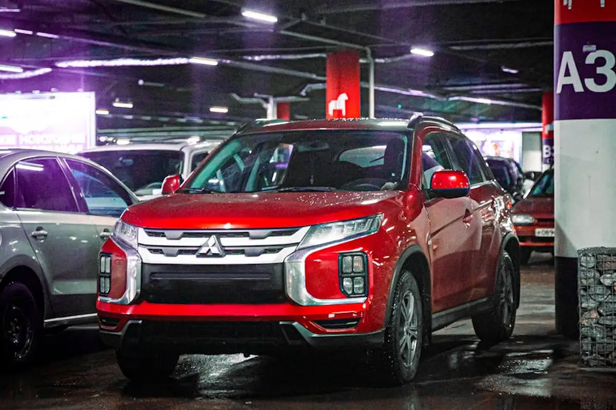 Red SUV parked in a dimly lit indoor garage among other vehicles, illustrating a garage setting where durable, safe flooring is essential for EV charging stations.