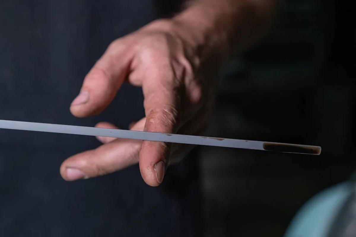 Close-up of a hand holding a thin, translucent cable (likely fiber optic) against a dark background.