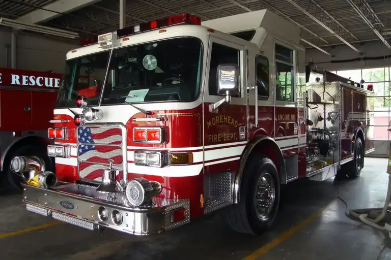 Red fire engine inside a fire station garage with equipment and hoses visible
