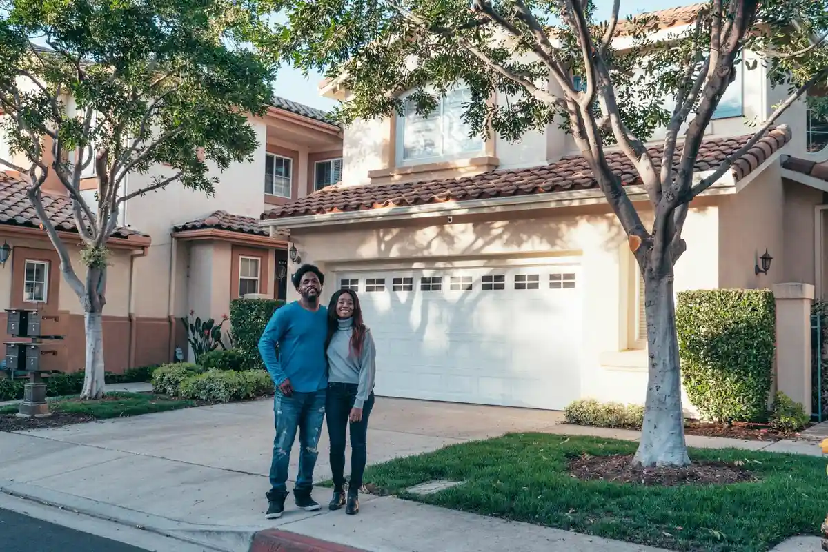 Couple standing in front of a two-car garage at a sunny suburban home.
