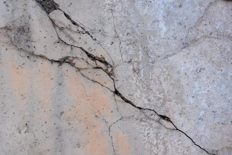 Close-up of a cracked concrete garage wall with visible fissures and staining.
