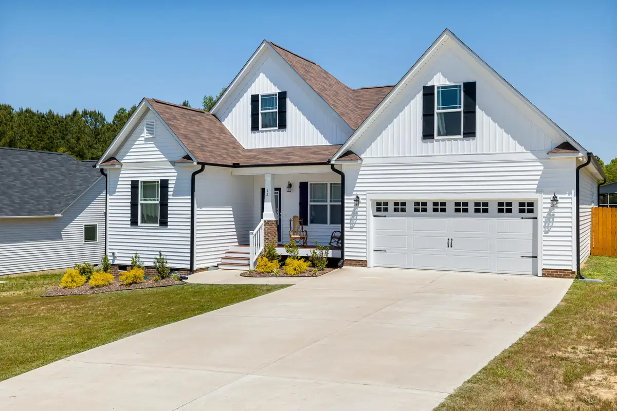 Sunny suburban home with a white two-car garage door and landscaped front yard.