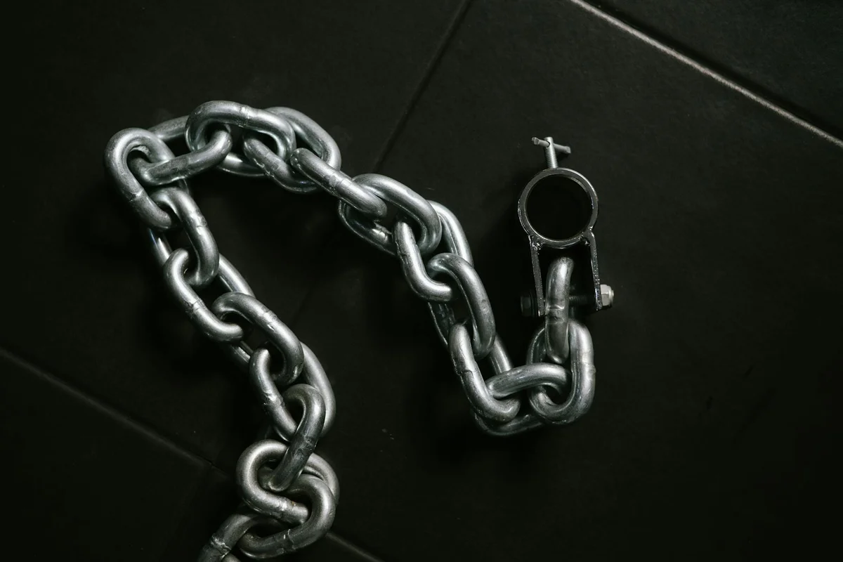 Close-up of a metal garage door chain with a latch on a dark surface