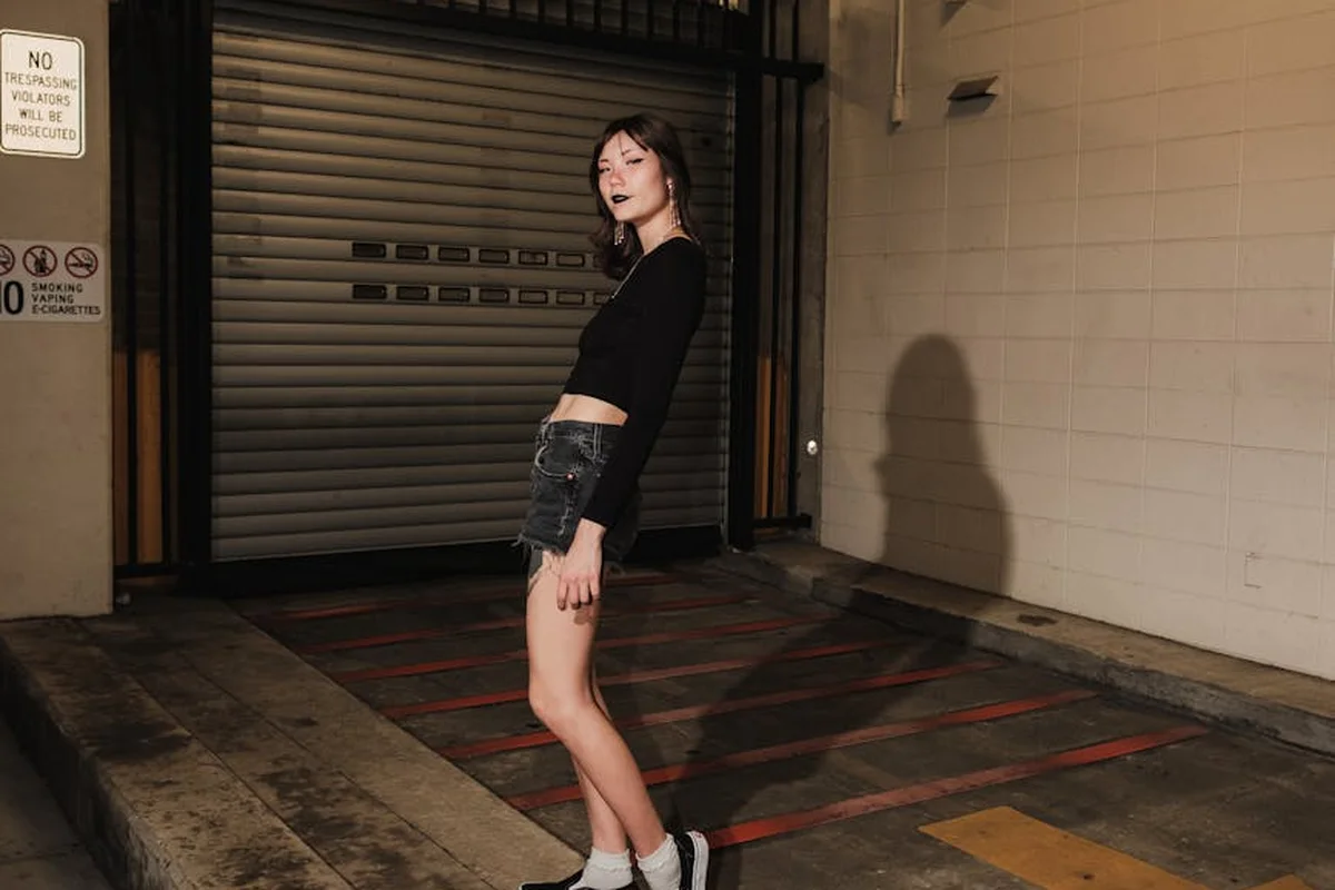 Person standing in a garage in front of a closed roll-up door, illustrating a setting for inspecting a garage door chain.