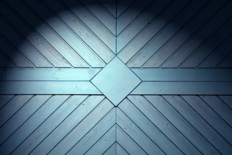 Blue-toned, closed garage door with diagonal wooden panels meeting at a central diamond shape.