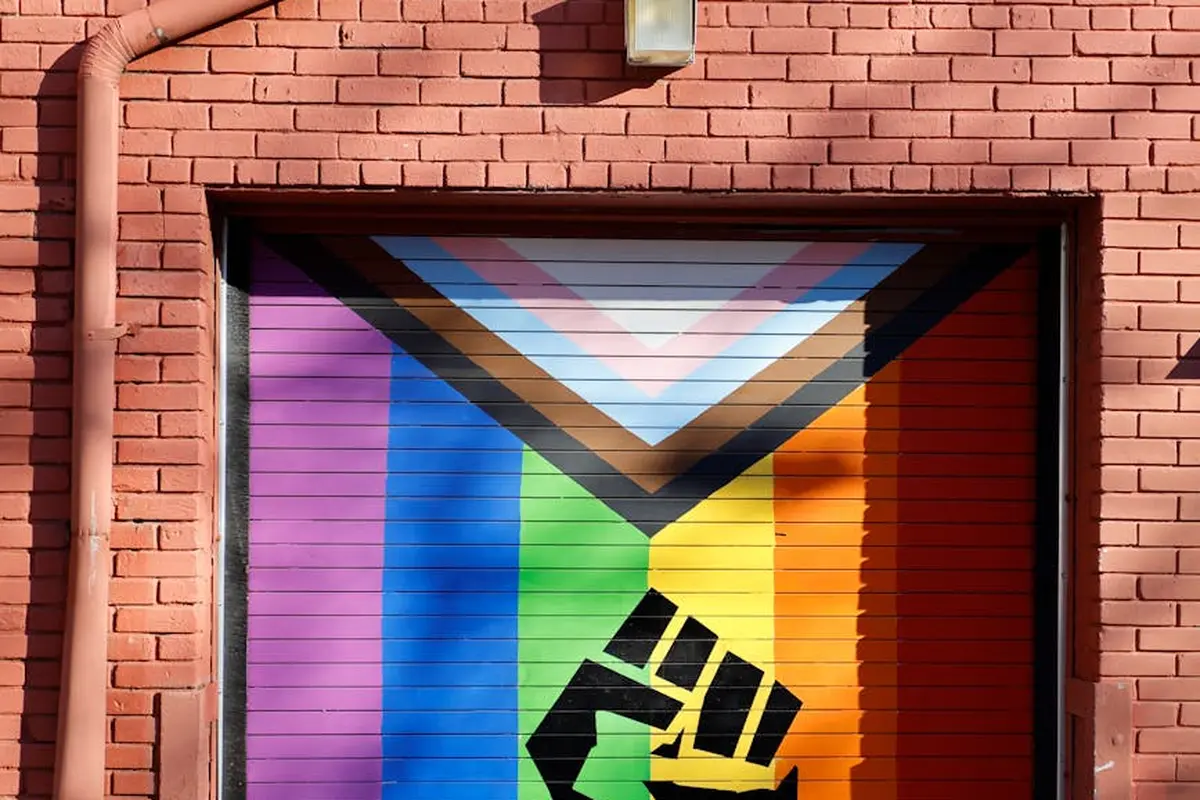 A garage door with a vibrant rainbow mural and a black clenched-fist graphic.