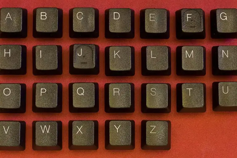 Close-up of a dark gray computer keyboard on a red background, symbolizing entering and changing codes for a garage door keypad or opener.