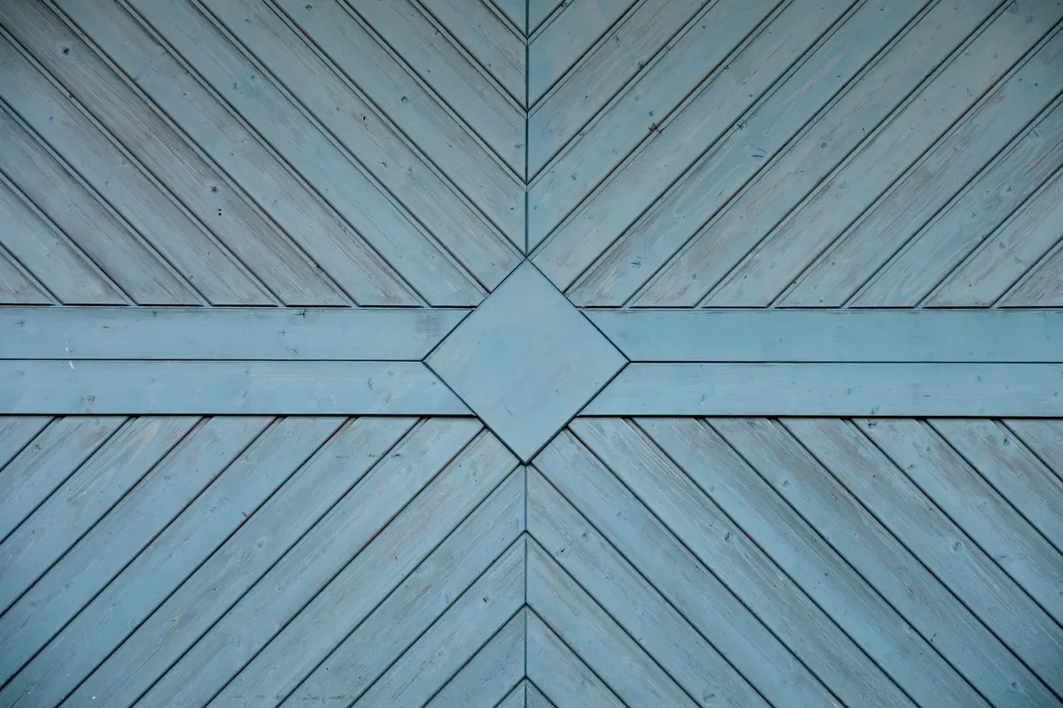 Blue wooden garage door with diagonal planks forming a geometric pattern and a central diamond