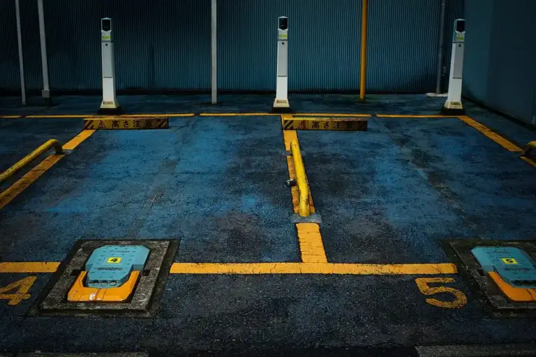 Industrial garage or parking area with numbered spaces and small electrical maintenance units on the floor, illustrating components involved in garage door opener power and troubleshooting.