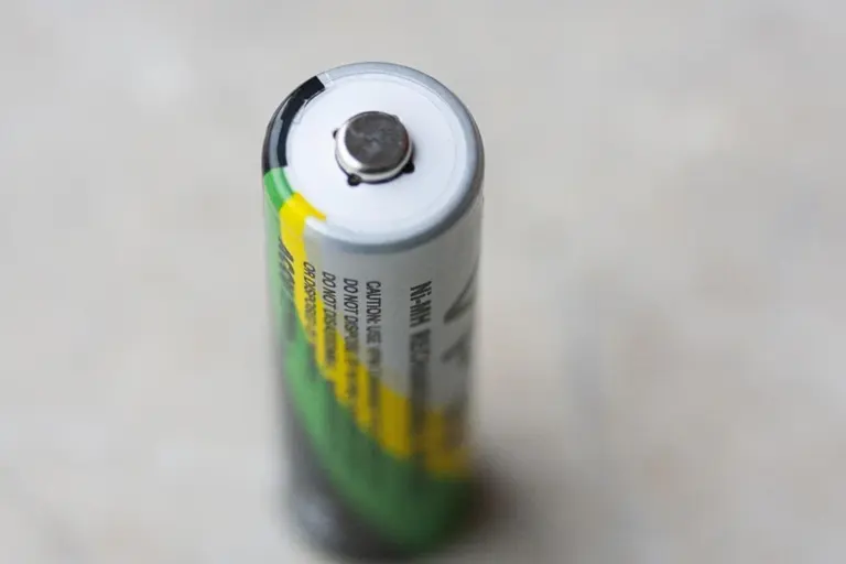 Close-up of a cylindrical household battery with a green and yellow label, viewed from the top