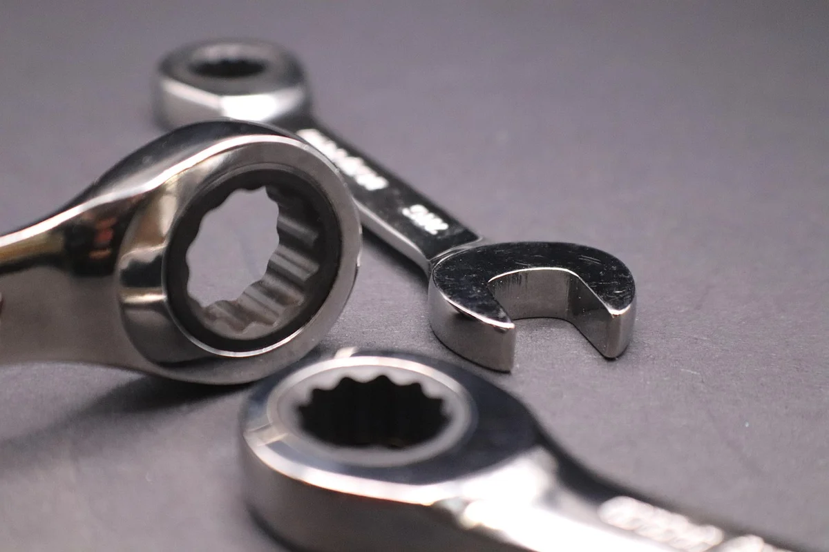 Close-up of chrome wrenches and socket pieces on a gray surface