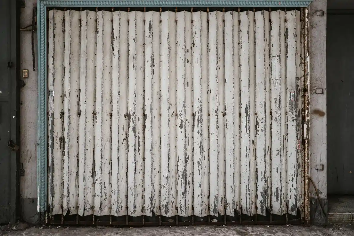 Weathered white rolling garage door with vertical panels and rust marks