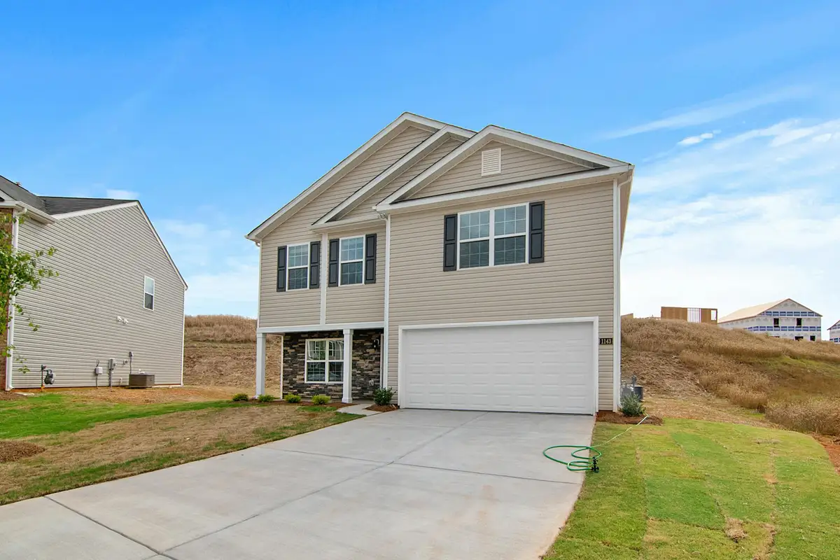 Suburban house with a two-car garage and a clean driveway; the garage door is closed.
