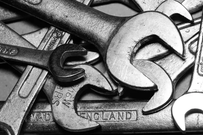 Close-up of wrenches and other metal tools stacked together, related to garage door springs.
