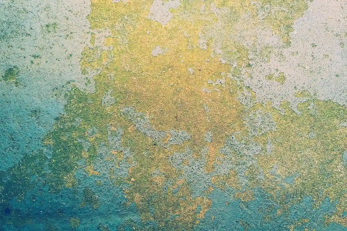 Close-up of a textured concrete garage floor with multicolor staining, emphasizing the surface that needs cleaning and prep before finishing.