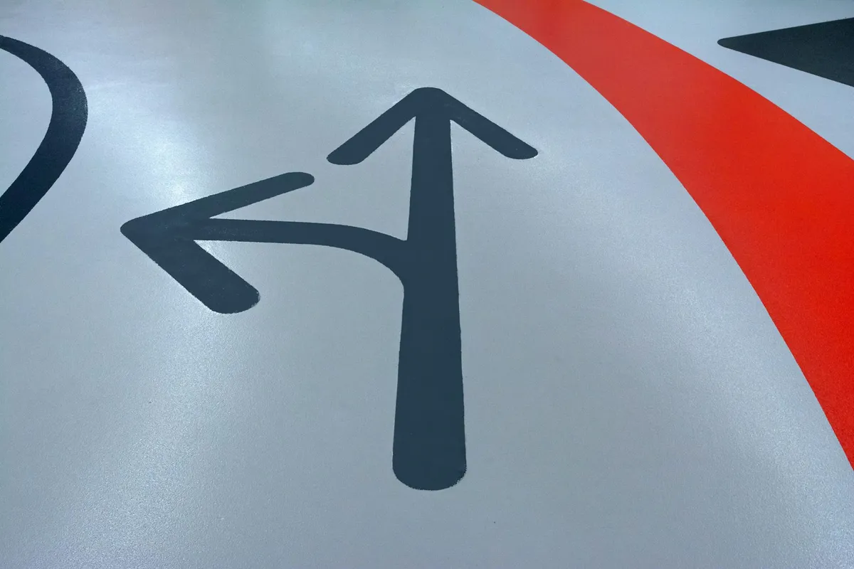 Close-up of a gray surface with black directional arrows suggesting a choice between flooring options.