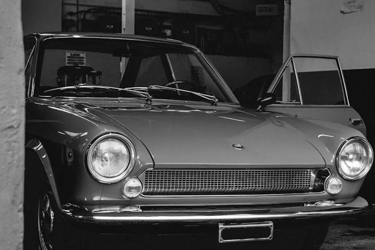Black-and-white photo of a vintage car parked inside a dimly lit garage.