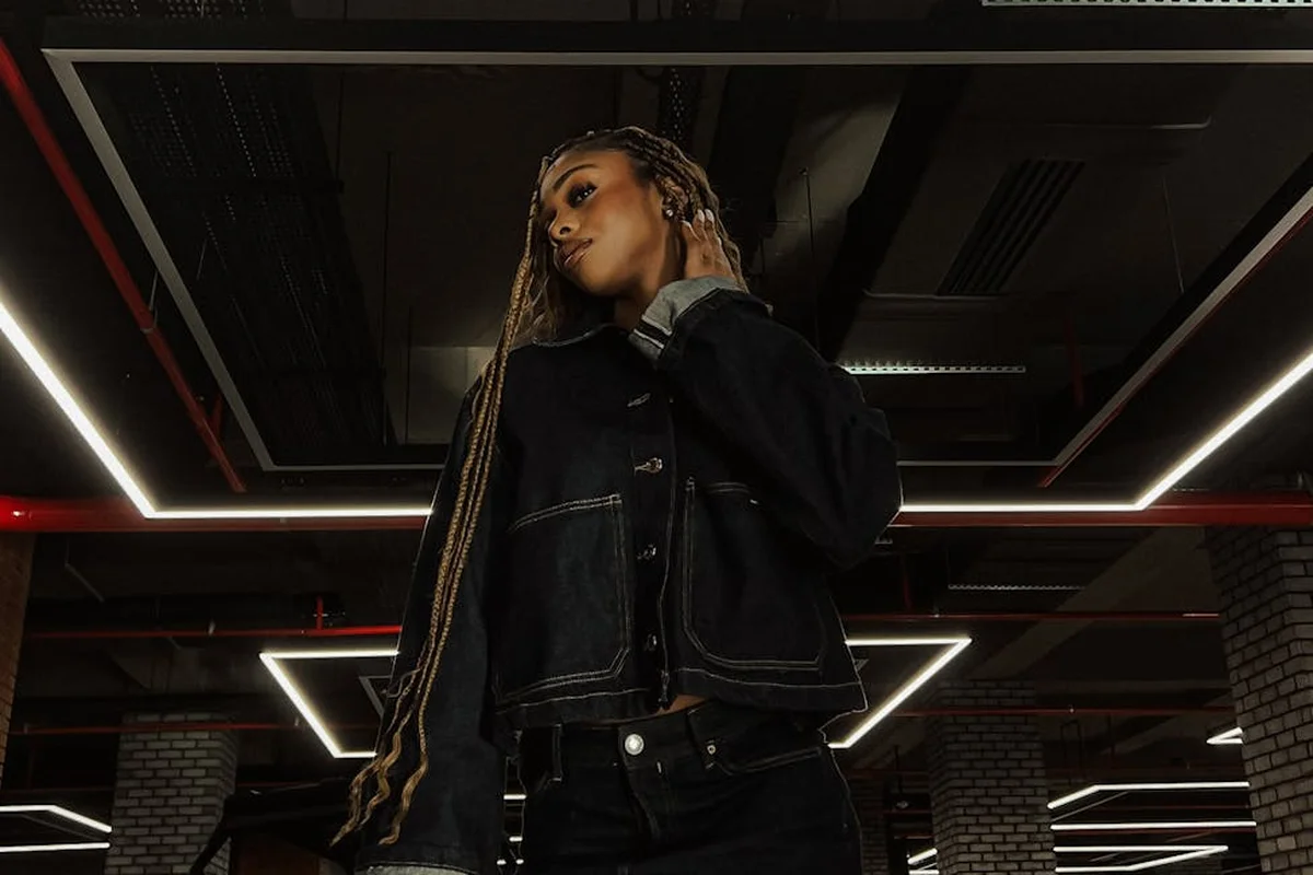 A person stands in a modern garage with exposed ceiling and linear LED lights forming a grid-like pattern, illustrating overhead lighting for shadow-free illumination.