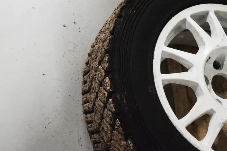 Close-up of a dirty tire and white wheel on a garage floor.
