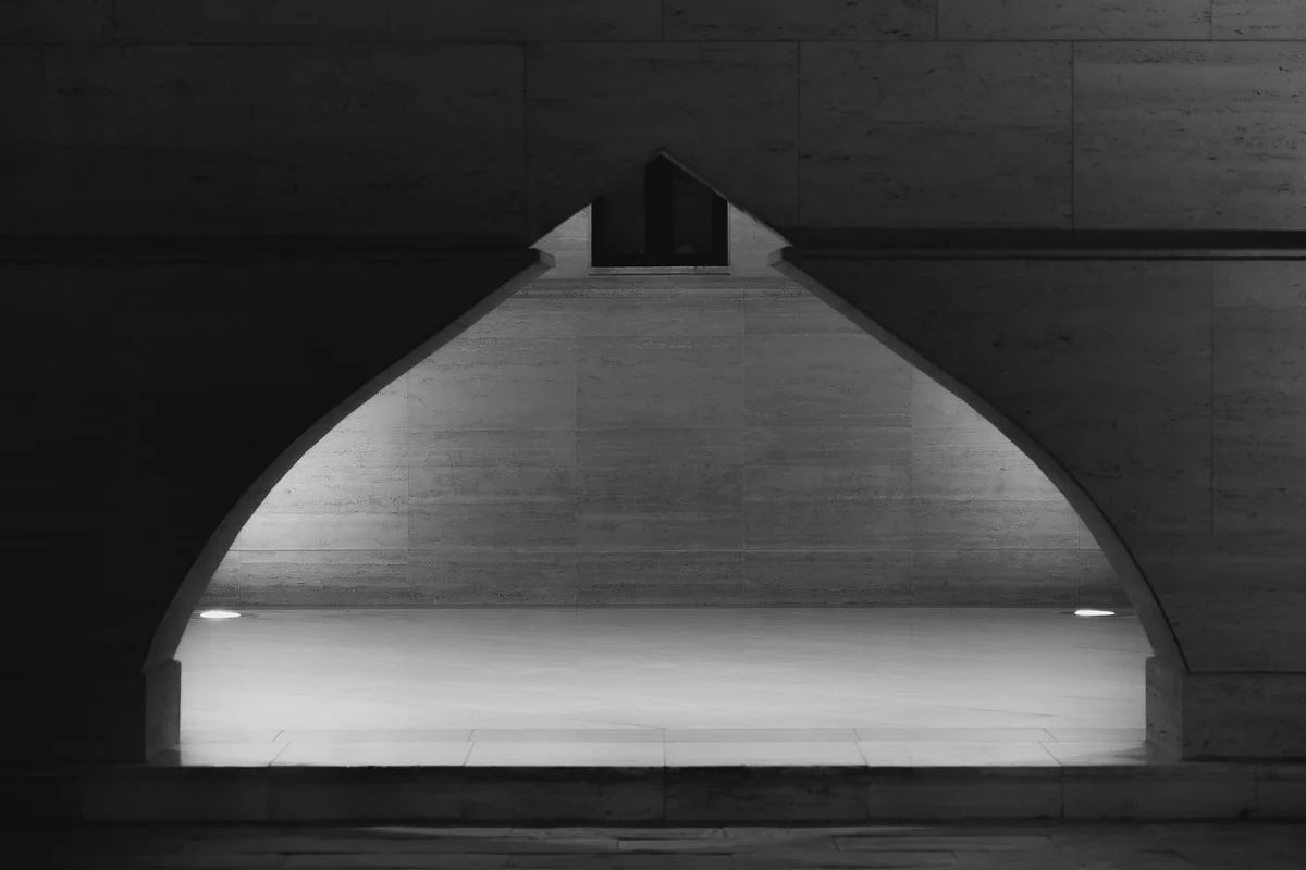 Concrete garage arch doorway with a bright floor in a dim space, shown in black and white.