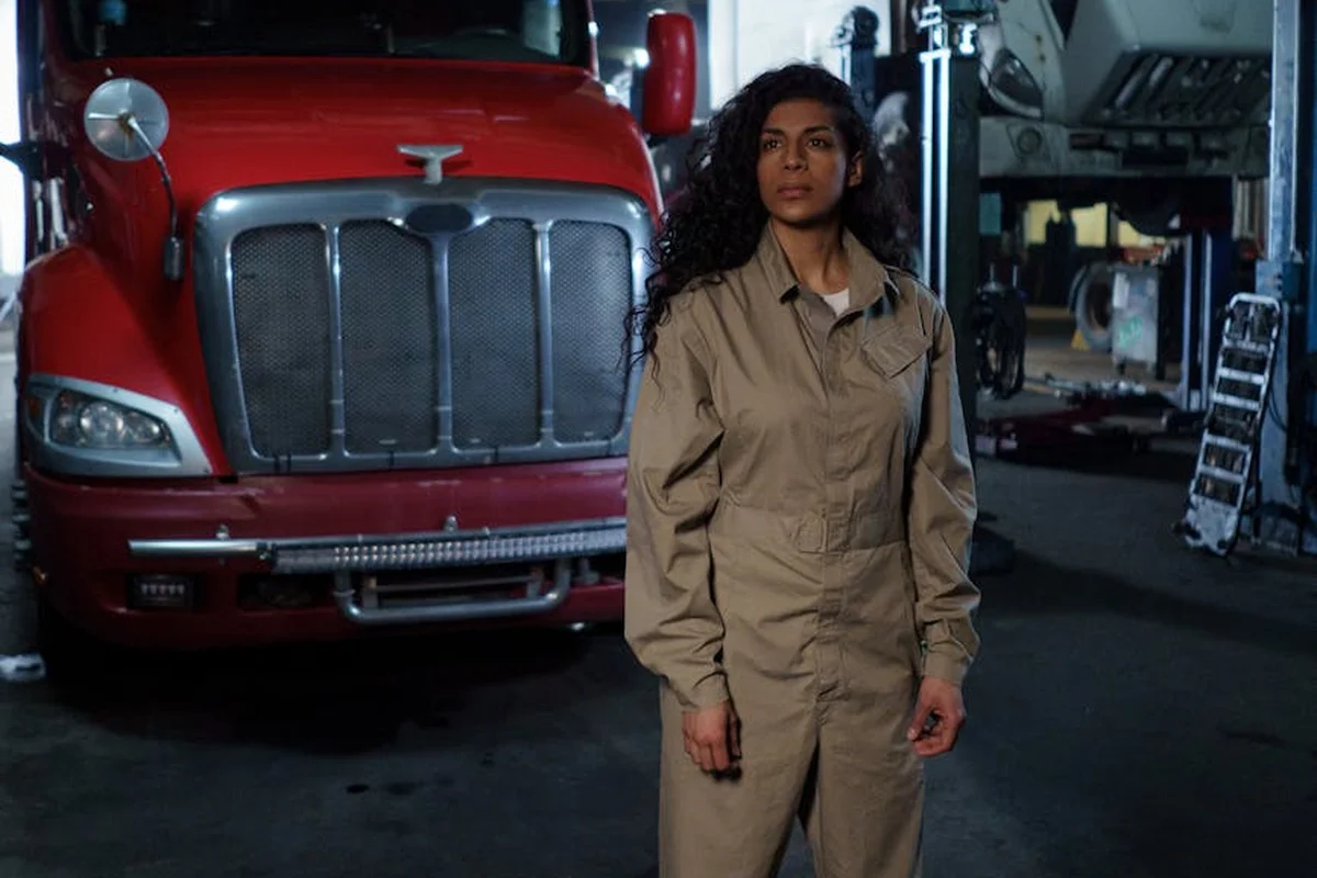A person in beige coveralls standing in a garage beside a red truck, illustrating garage space in home square footage.