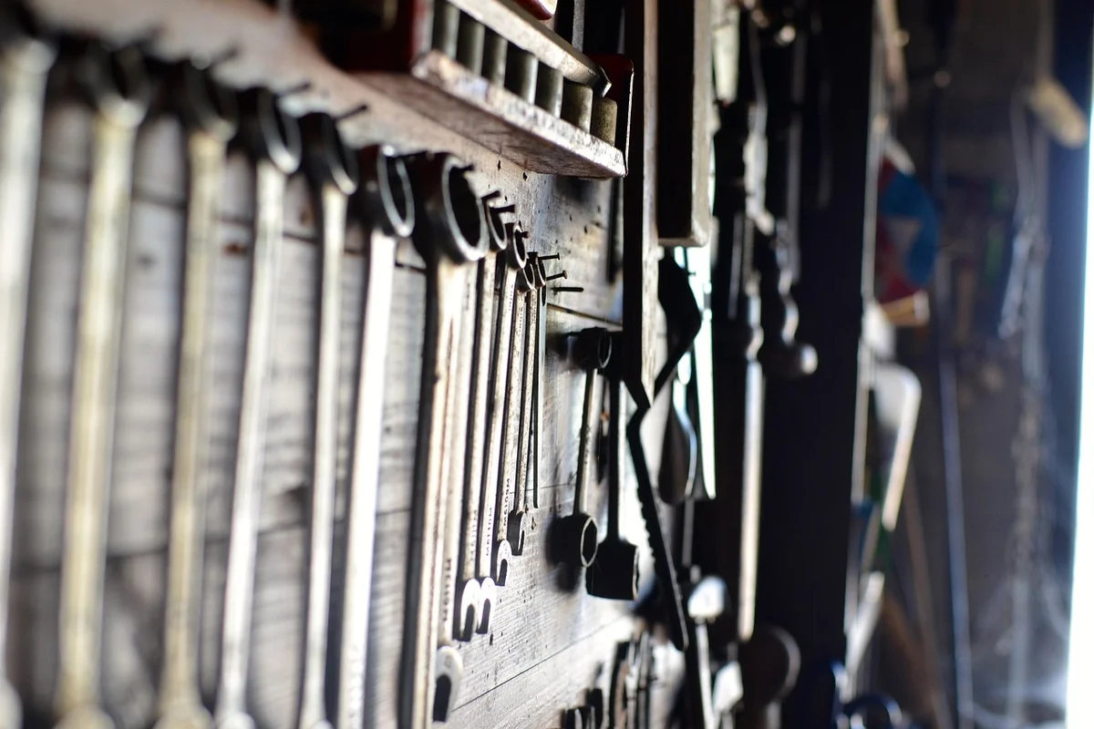 Close-up of a pegboard in a garage with rows of wrenches and other tools hanging.