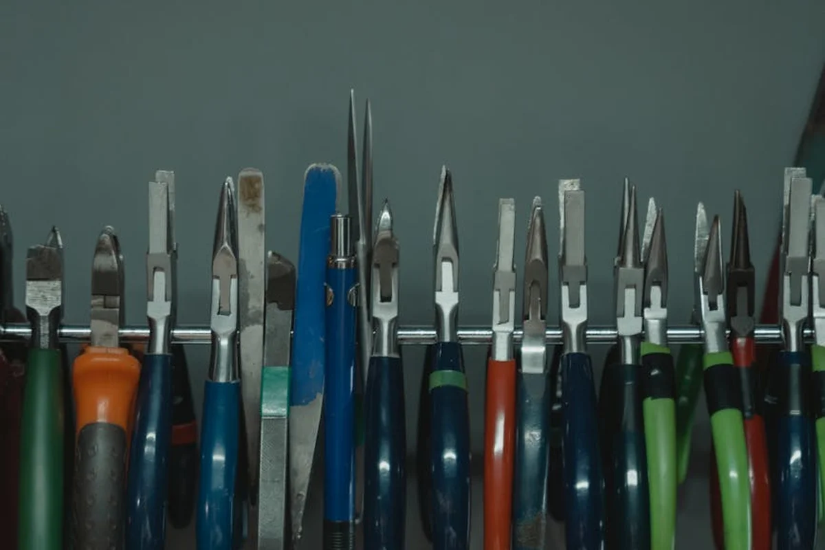 Row of screwdrivers and hand tools with pointed blades stored upright in a wall-mounted rack