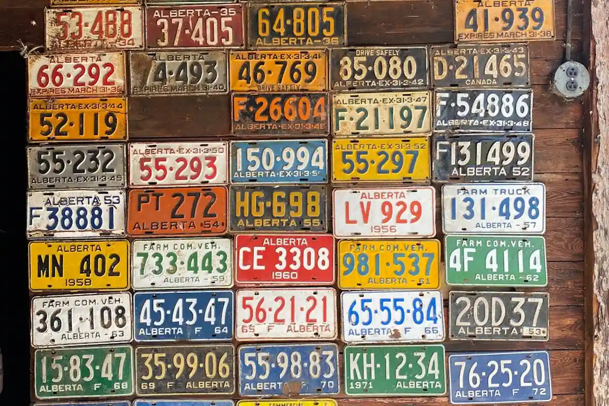 Wall covered with colorful vintage license plates arranged in a grid on a garage wall.