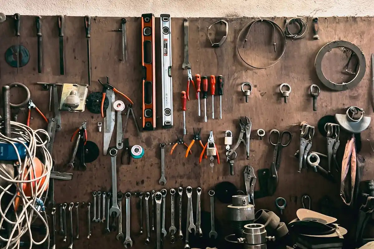 A well-equipped workshop wall with a pegboard and hanging tools—level, tape measures, wrenches, pliers, and clamps—ready for framing garage walls.