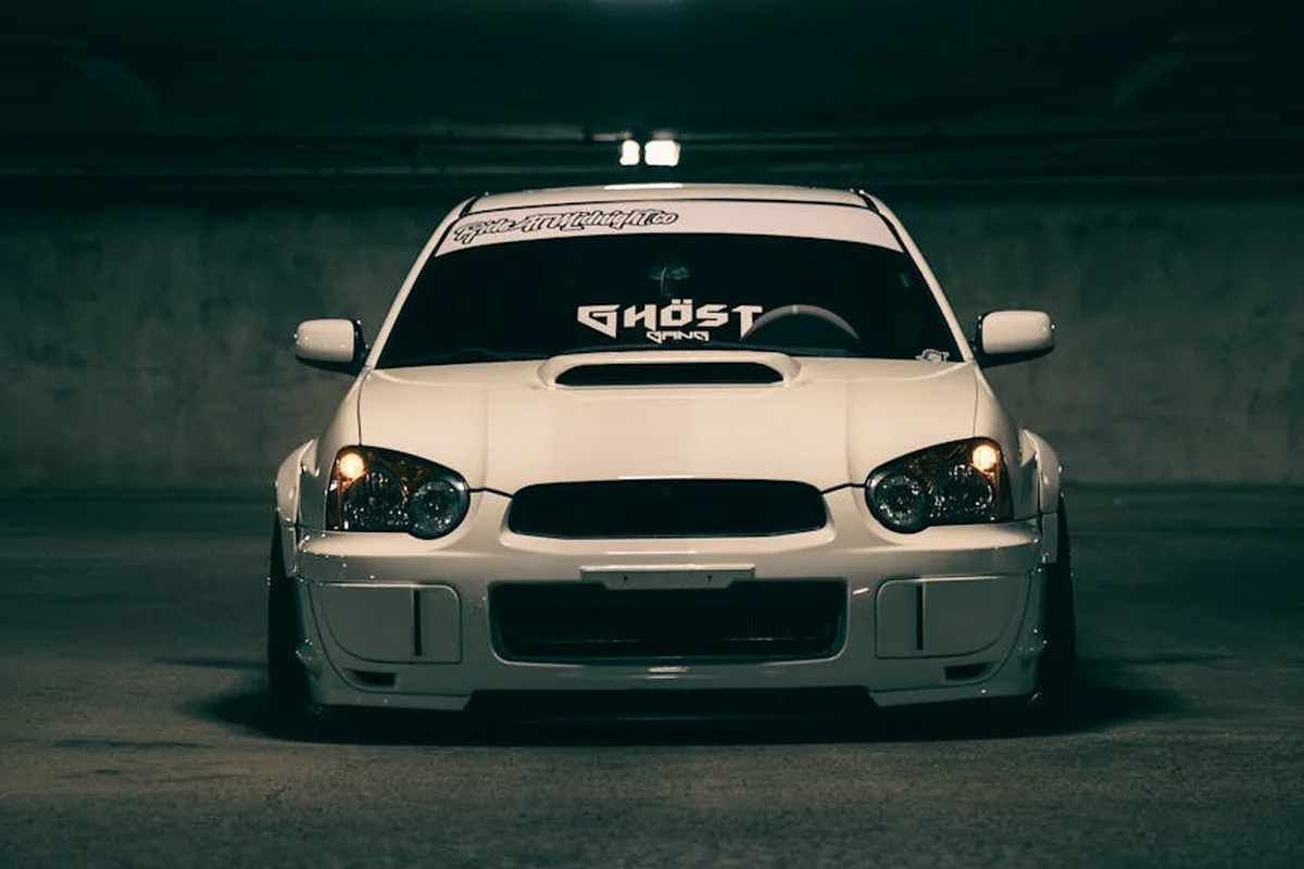 White car with hood scoop parked in a dimly lit underground garage