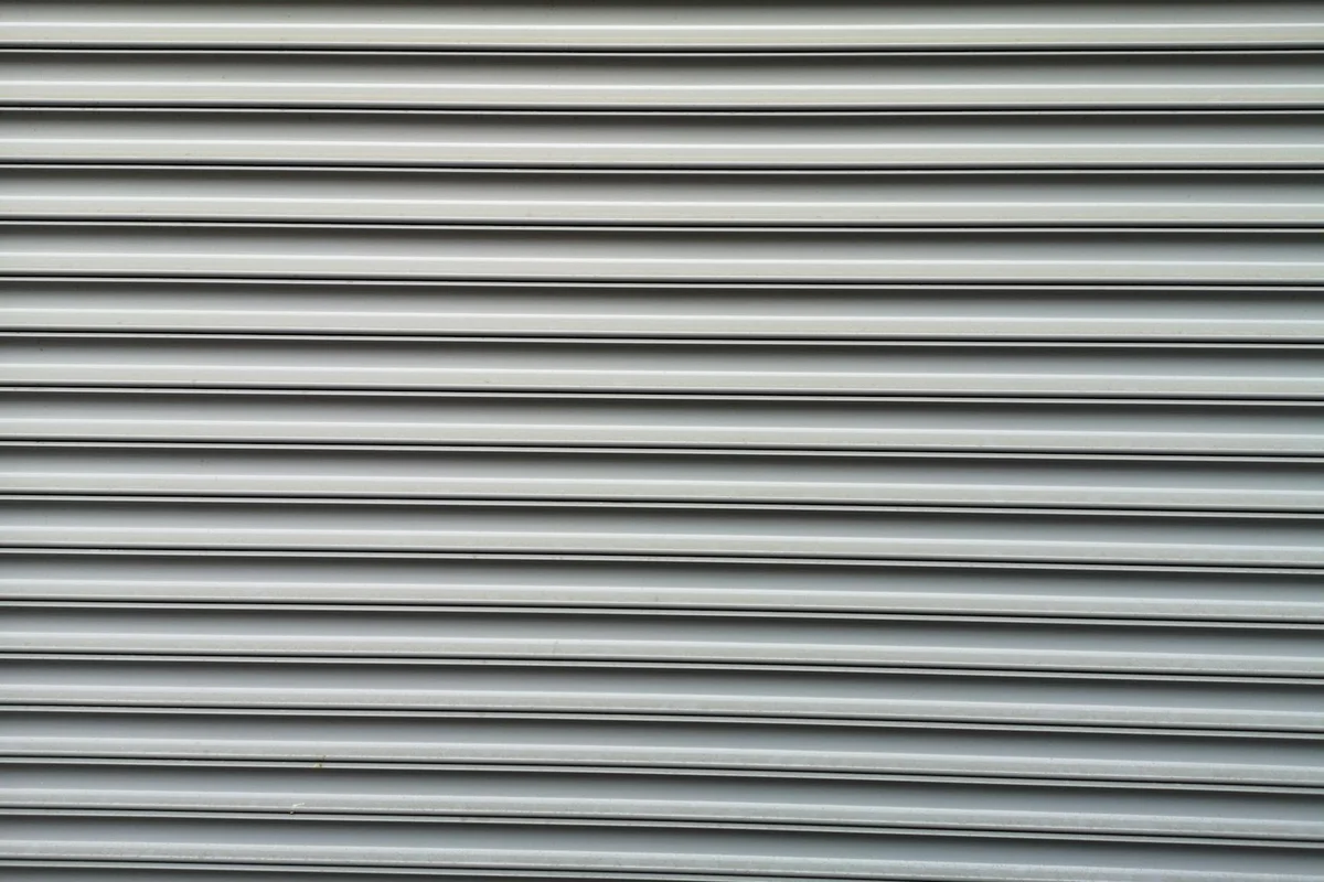 Gray metal garage door with horizontal sectional slats.