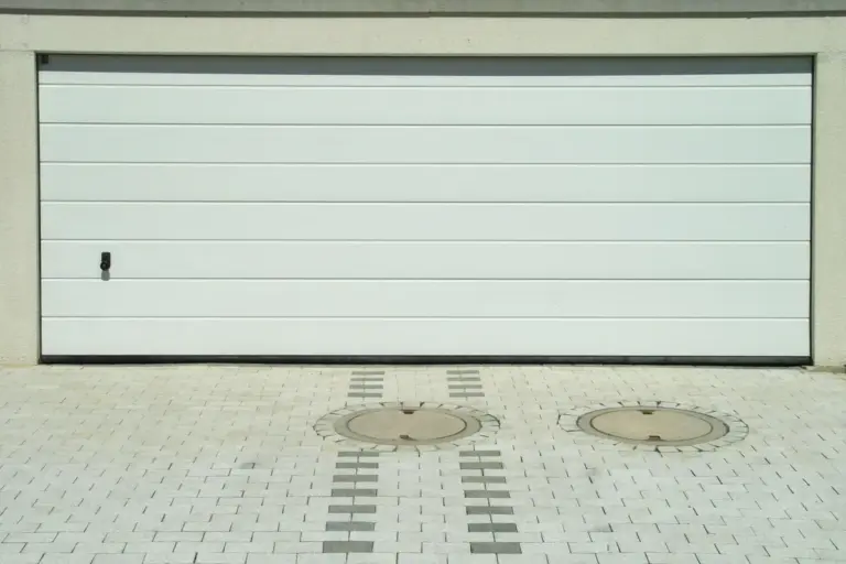 Closed garage door with a flat, paved driveway, illustrating a starting point for accessibility upgrades in garage conversions.