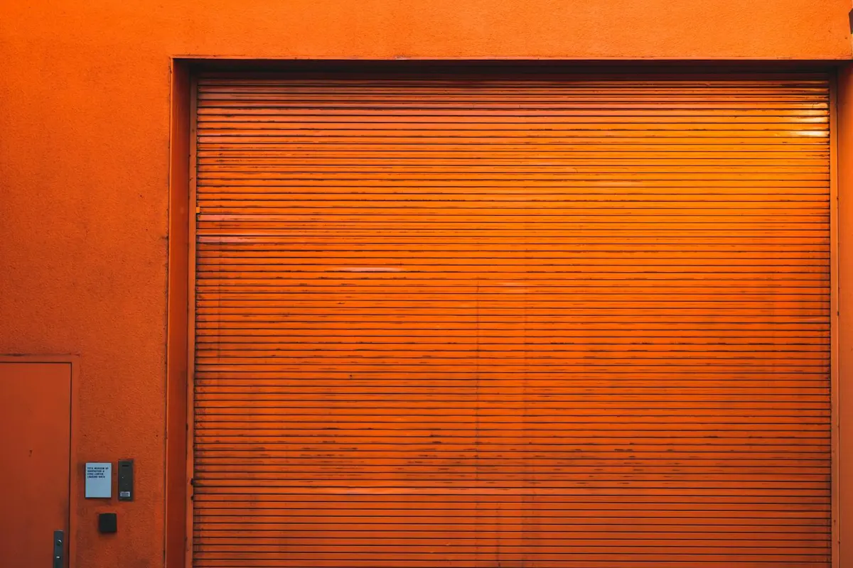 Closed orange rolling garage door with a small control panel on the left