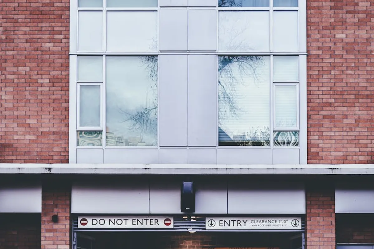 Brick storefront garage entry with large windows above and Do Not Enter / Entry signs, typical of a residential or commercial garage door