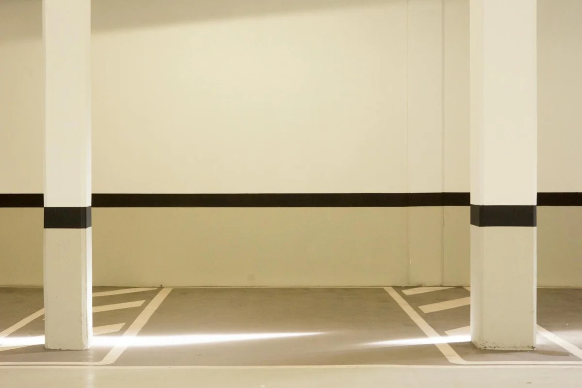 Parking garage with white columns and clearly marked spaces, illustrating a clean, durable floor surface suitable for EV charging stations.