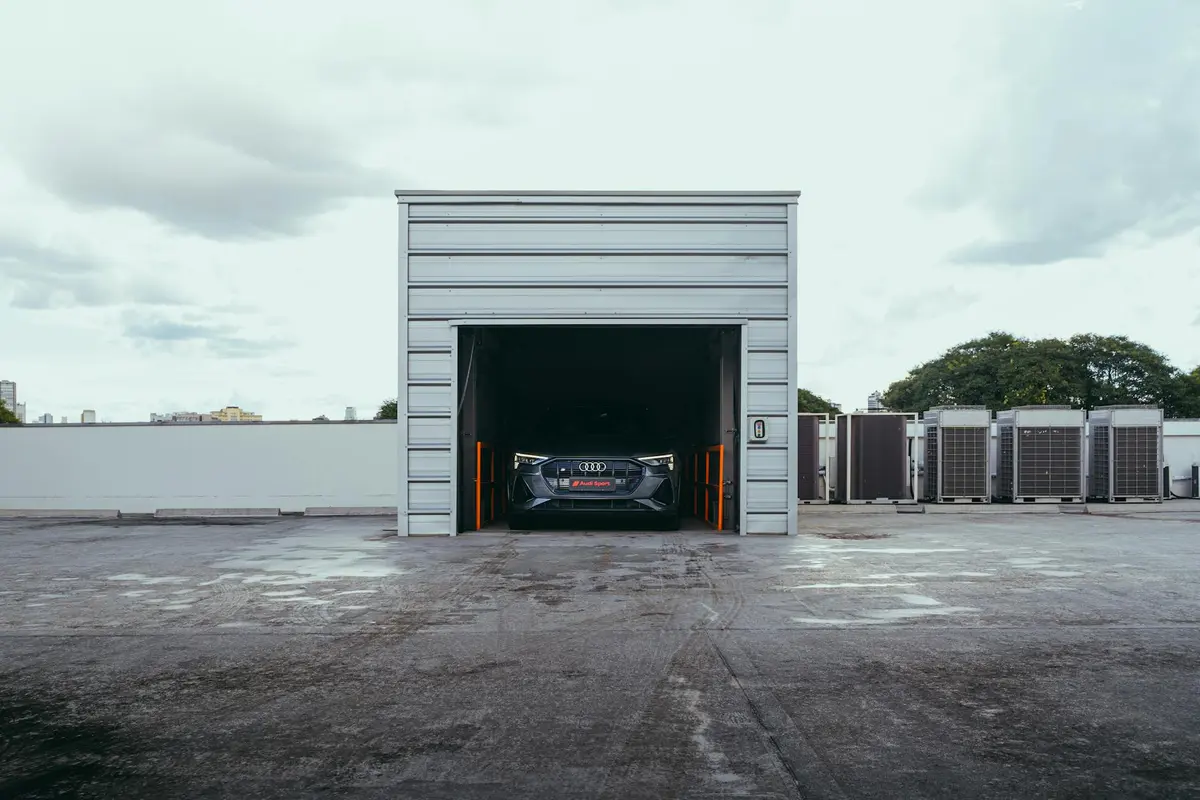 A car is parked inside a small metal garage bay on a flat rooftop, with HVAC units visible along the side.