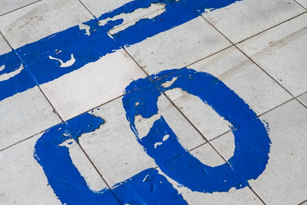 Close-up of a concrete garage floor with bold blue paint forming large letters