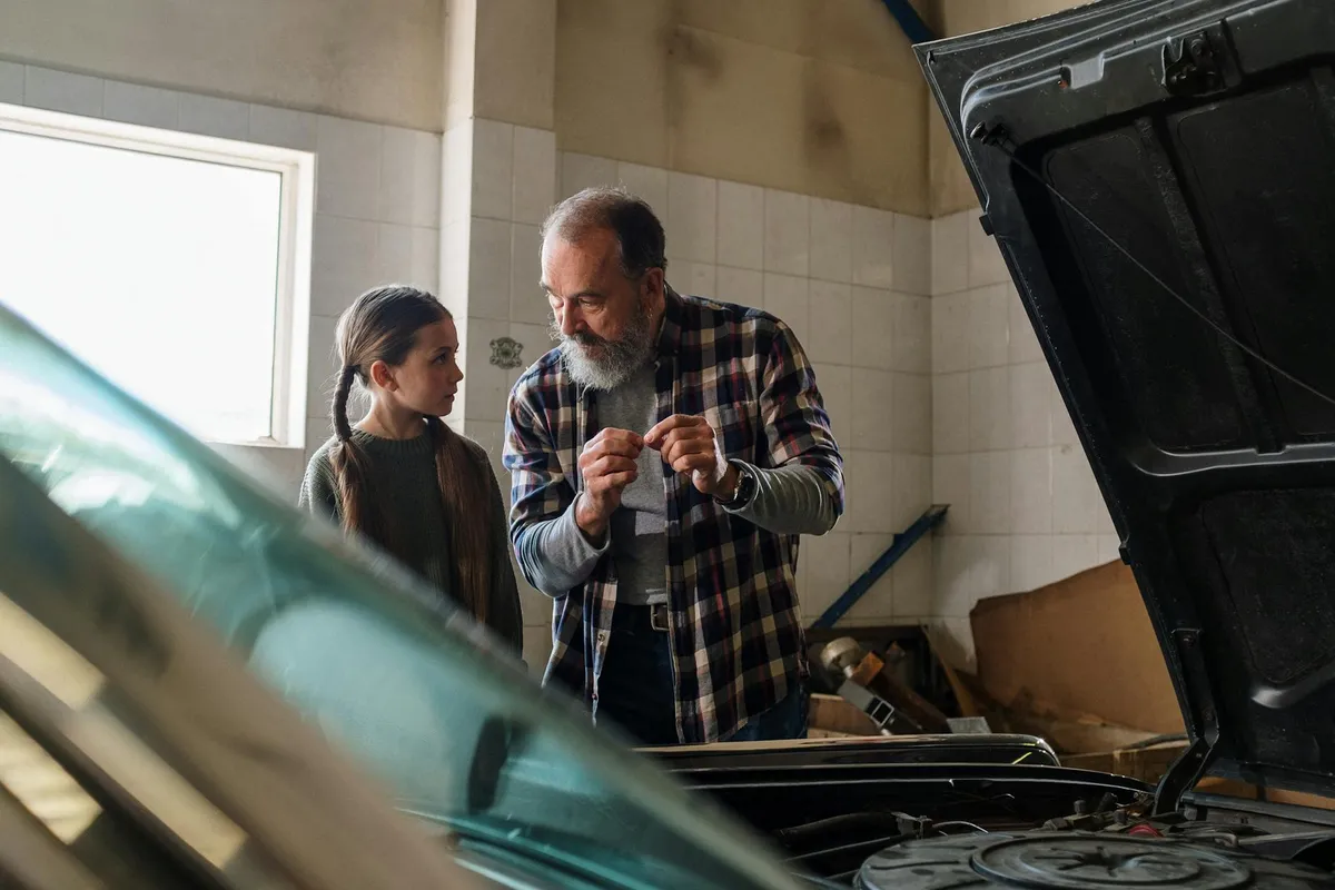 Two people in a garage near an open car hood, discussing safe heating and insulation.