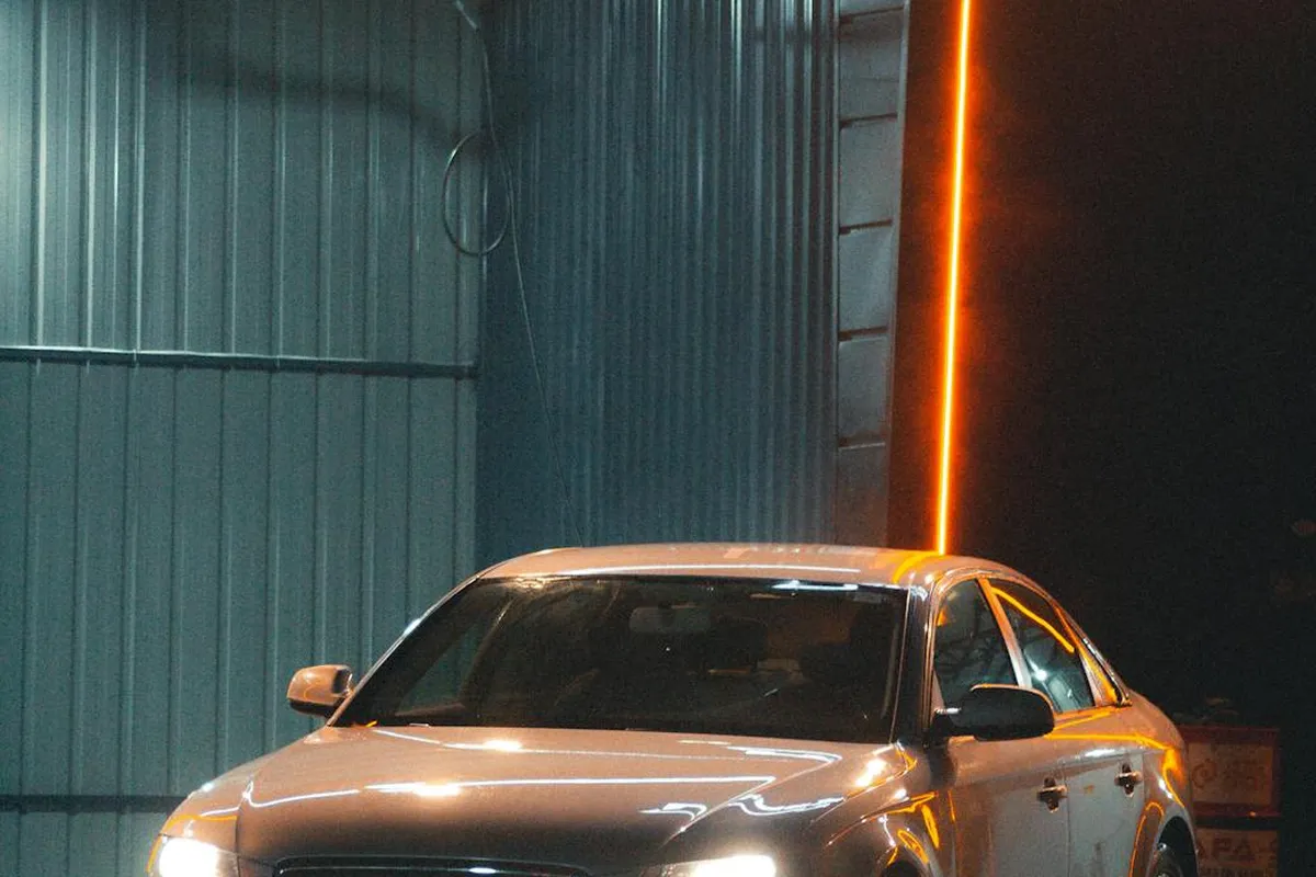 White car in a dim garage with an orange vertical LED strip along the wall.