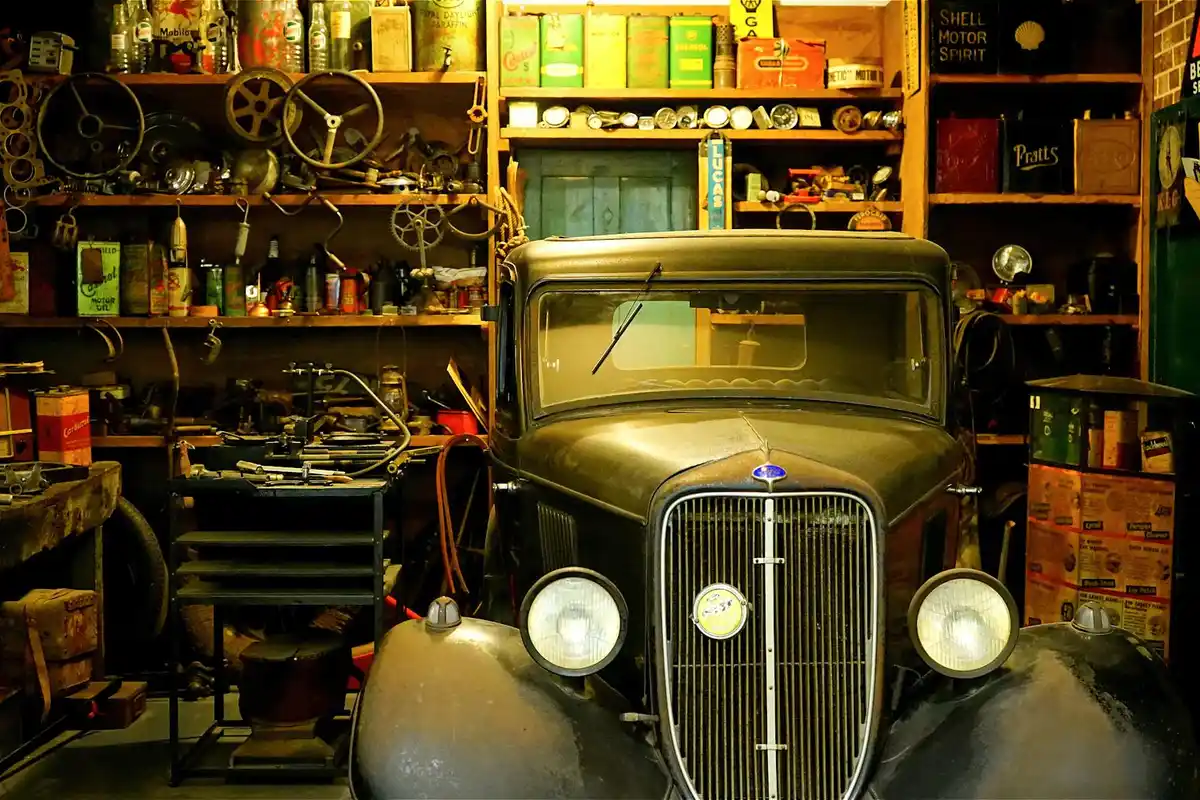 Vintage car in a cluttered garage with shelves of tools and boxes, illustrating a typical maintenance area where water intrusion can occur.