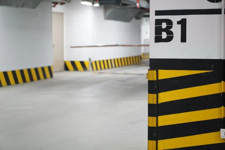 Interior parking garage with a large pillar marked 'B1' and black-and-yellow safety stripes in the foreground
