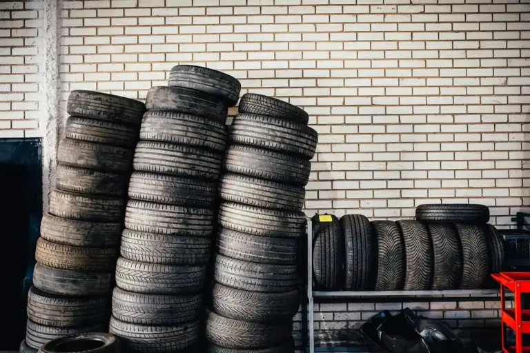 Tall stacks of tires leaning against a white brick wall inside a garage