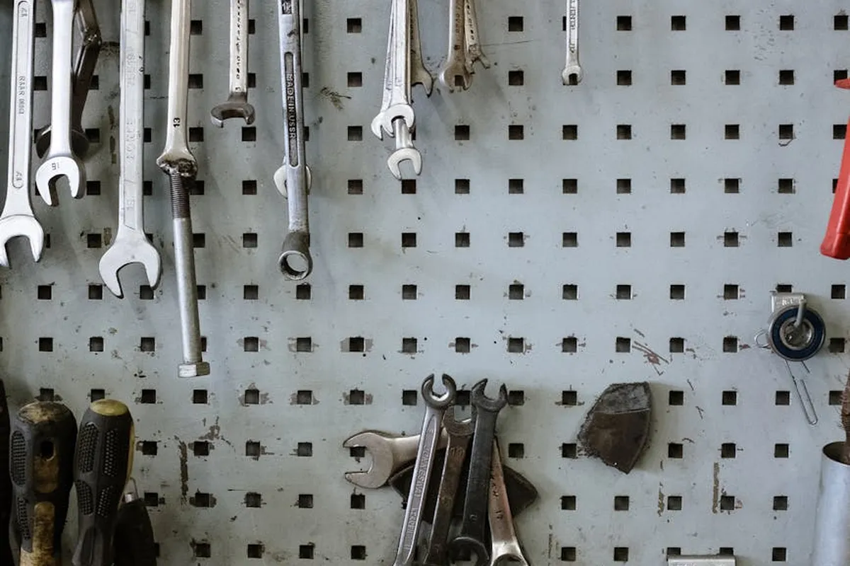 Pegboard wall in a garage with wrenches and other hand tools hanging from hooks