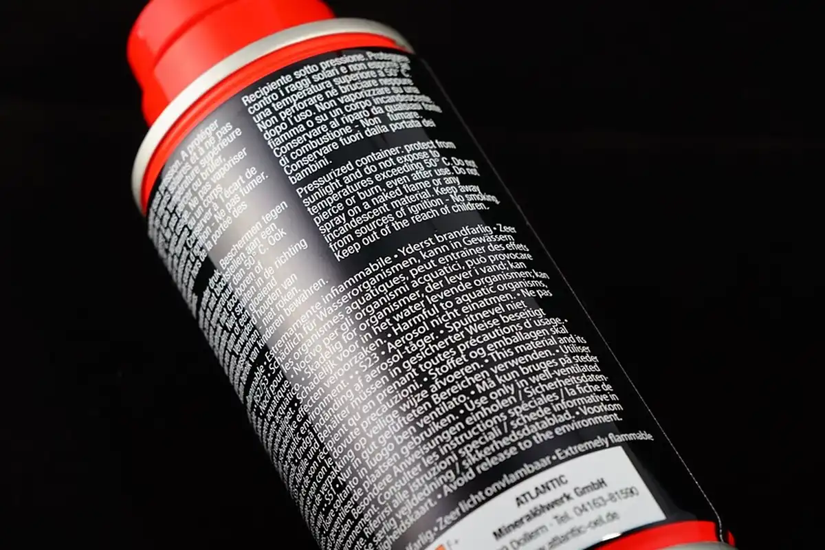 Close-up of a red-capped gas can with a dense warning label printed along its black body